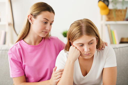 Young woman consoling worried sister or friend. Depression and mental health concept.