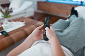 Male Lying Down On Sofa And Changing Television Channel