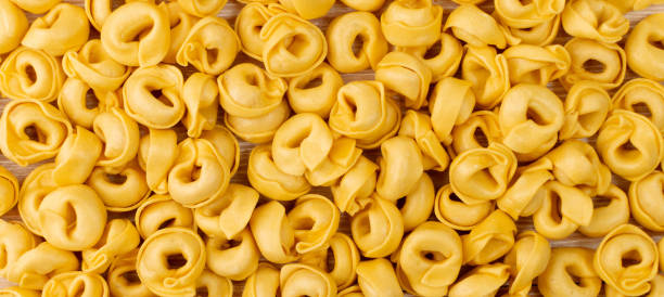 istock Raw Tortellini Texture Background, Italian Ravioli Pattern, Stuffed Dumplings Banner, Fresh Yellow Egg Tortellini 1573656042