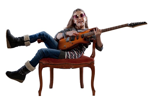 Little girl on a baroque velvet armchair, playing pop-rock star with an electric guitar and sunglasses, captivating an imaginary audience