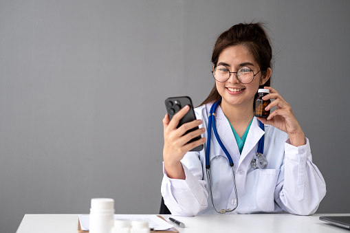 Female Young Asian doctor making video call with patient by smartphone cell phone laptop tablet