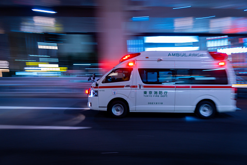 A Japanese ambulance racing through the streets of Roppongi, Tokyo at night, on its way to an emergency, June 10th 2023