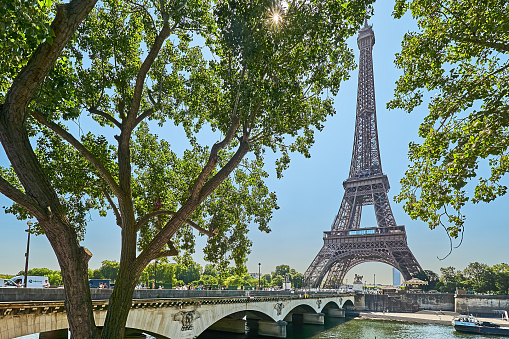 Paris, France - July 11, 2023: Traffic on the Pont d'léna bridge on the Seine. In the background the Eiffel Tower against the light in the morning.