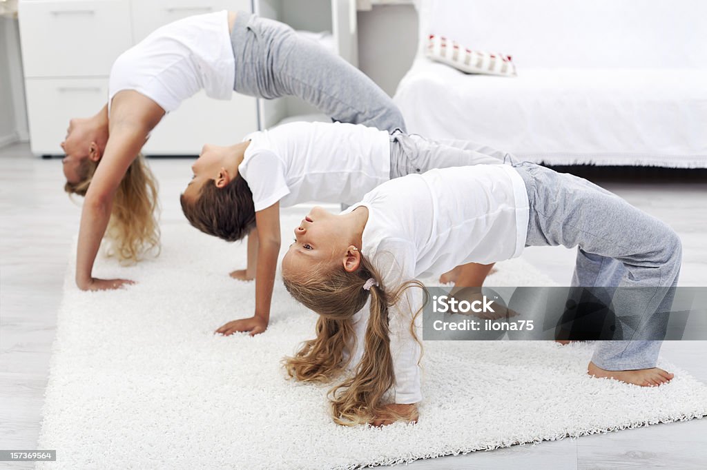 Woman and kids doing gymnastic exercises at home Woman and kids doing bridge stretch gymnastic exercises at home Active Lifestyle Stock Photo