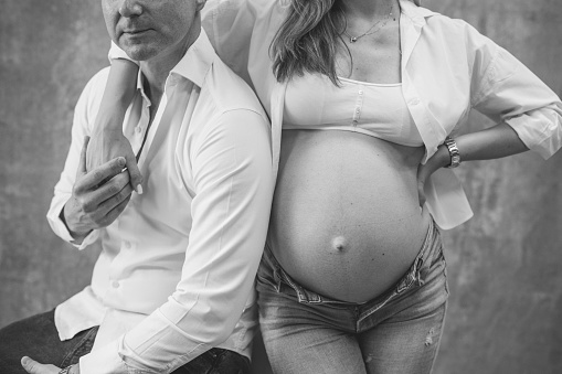 Black and white studio shot of happy pregnant couple