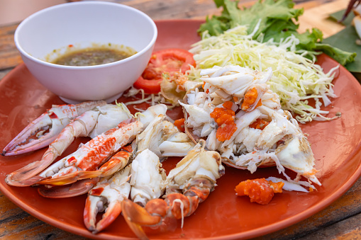 Steamed sea crab with spicy seafood sauce serving with shredded cabbage and tomato.