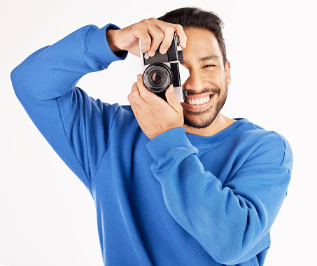 Camera, photographer and portrait of asian man in studio for photoshoot, creativity and paparazzi. Happy journalist, photography and shooting with vintage equipment for production on white background