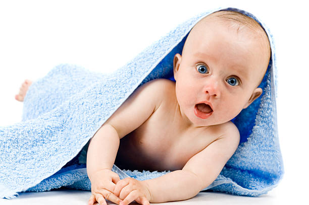 Blue-eyed baby in rug with surprised expression stock photo