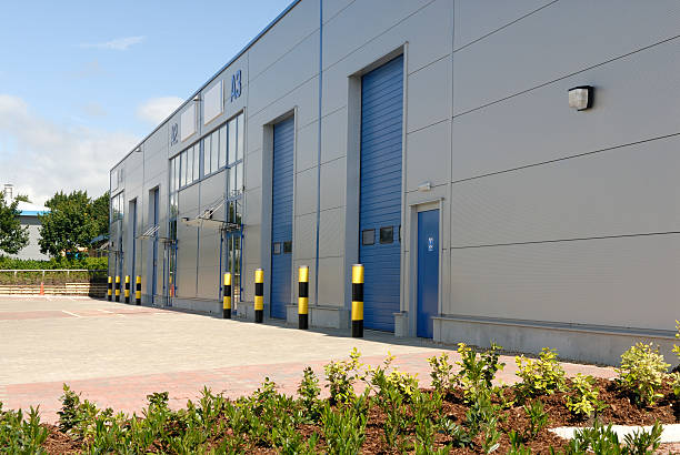 Outside of a big industrial warehouse unit with blue doors Modern industrial business unit. industrial style photos stock pictures, royalty-free photos & images