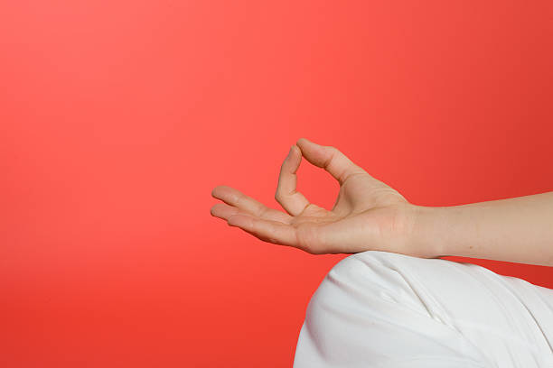 A young woman in a white t-shirt sitting in the lotus position meditates holding fingers in yoga sign with rays of abstract circulating colored energies around. Spirituality, awakening, enlightenment