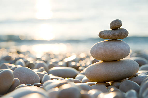 balanced stones on a pebble beach during sunset. - strand fotos stockfoto's en -beelden
