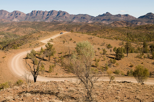 A 4x4 in the distance on a winding desert road in Southern Australia.