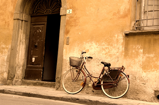 Rome, Italy - June 6, 2022:Weathered doorway and poyyed plants on sloped street in Rome, Italy.