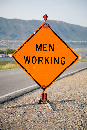 An orange roadside construction sign with the words 