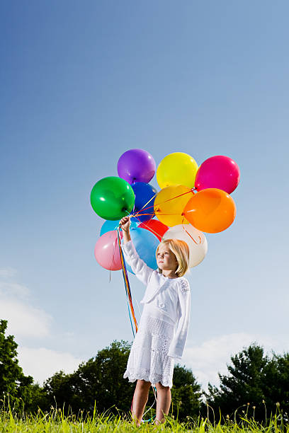 istock Little girl with multicolored balloons feels the wind 157373814