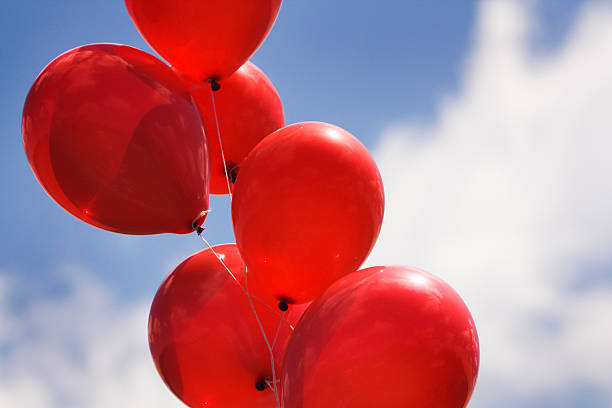 Helium Party Balloons Against Sky for Celebration Events Subject: The festive atmosphere of a bundle of red helium balloons. helium balloon stock pictures, royalty-free photos & images