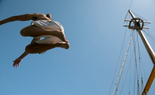 jumping into the ocean via the upper deck of a sailboat. Motion blur on the model. Similar images:   