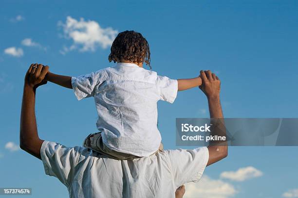 Vista Traseira Do Menino Com Ombros Do Pai Sob Céu Azul - Fotografias de stock e mais imagens de Criança