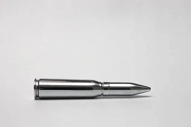 Photo of Shiny chrome bullet against gray background