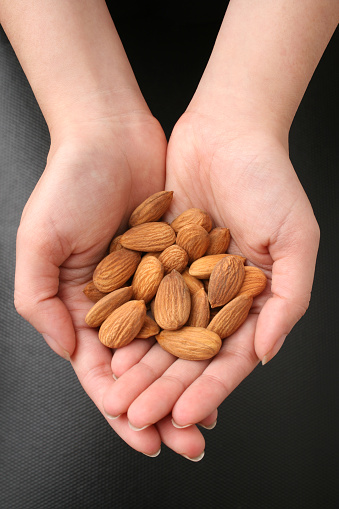 Top view of young woman hands holding almonds. Shallow depth of field