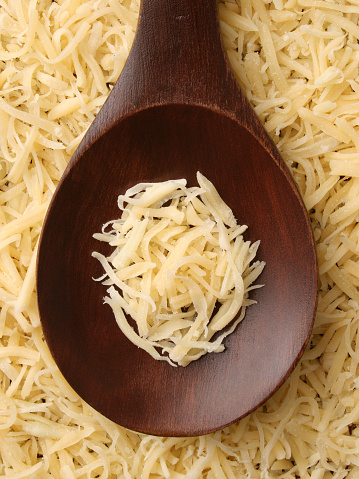 Top view of wooden spoon with grated cheese on it