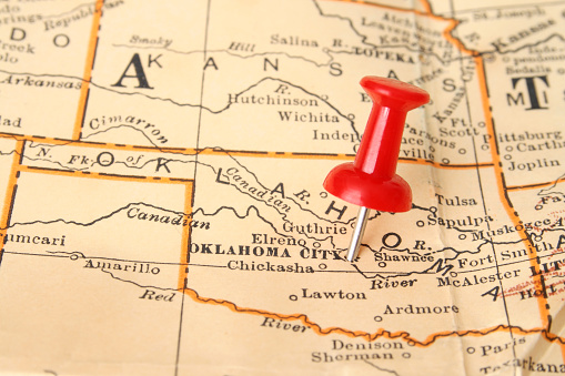 Pushpin pointing Oklahoma city, Oklahoma state capital, over more than fifty years old map