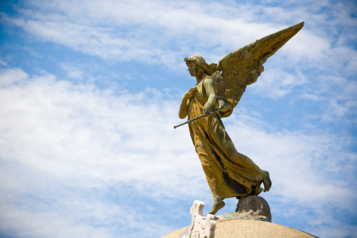 Trumpeting Angel Statues Seem to be making a Heavenly announcement against a deep blue sky.