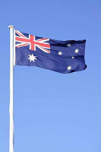 The Australian flag against clear blue sky.