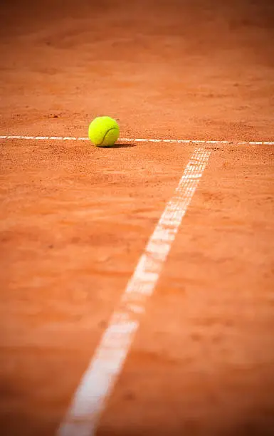 Tennis ball on near baseline of tennis clay court.