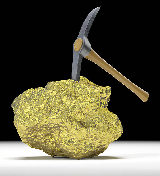 A golden nugget and a pick on a white table A large solid gold nugget with an embedded pick axe. Very high resolution 3D render. pick axe stock pictures, royalty-free photos & images