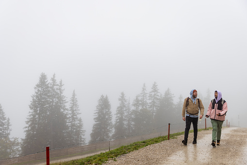 A full length wide view of a same sex LGBTQI+ male couple are tourists on vacation in Garmisch-Partenkirchen, Germany. They are walking side by side at the top of the Zugspitze mountain.