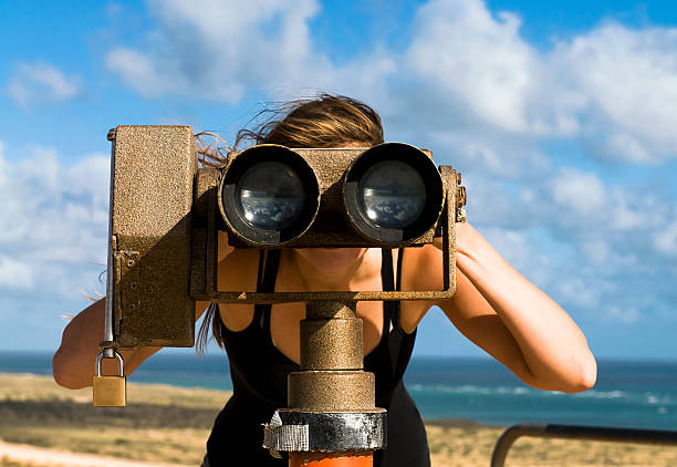 Looking Through A Telescope A young woman plays with a tourist telescope / binocular set. looking through an object stock pictures, royalty-free photos & images