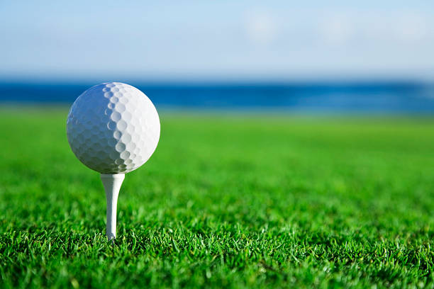 golfball auf tee mit blick aufs meer - golf golf ball tee green stock-fotos und bilder