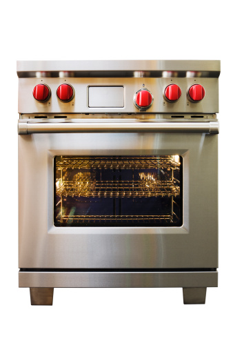 A residential or commercial stainless steel stove, convection oven and gas range, an essential appliance in a gourmet kitchen. The single piece of heavy duty household equipment has red knobs and an electronic control panel for cooking and baking. Cut out and isolated on a white background with no people.