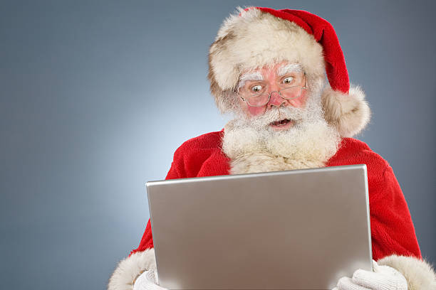 Santa is surprised by something on his laptop stock photo