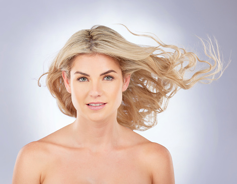 Portrait, woman and beauty of hair in wind on studio background for cosmetic growth, keratin treatment or shine. Face of female model with blonde haircare, curly waves and aesthetic texture in breeze