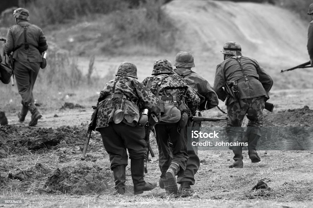 WW2 Attacking Troops. German era WW2 re-enactors advance towards the enemy.Major re-enactment battle at the War and Peace show.Picture has been aged to give the feel of a vintage photo. World War II Stock Photo