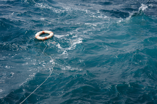 Single life buoy floating on deep and stormy ocean.