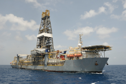 A drill ship at open ocean drilling location. Ship has helideck at bow and a double drill tower. Drill ships can drill in deeper water than many other offshore drilling platforms. They are often used for exploratory drilling as well as production well and now for oil well blow out recovery. A type of off shore oil rig.