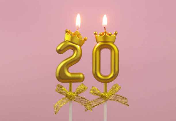 Gold birthday candles burning on pink, number 20. stock photo