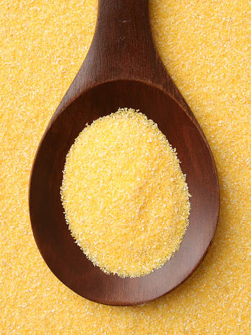 Top view of wooden spoon full of corn flour