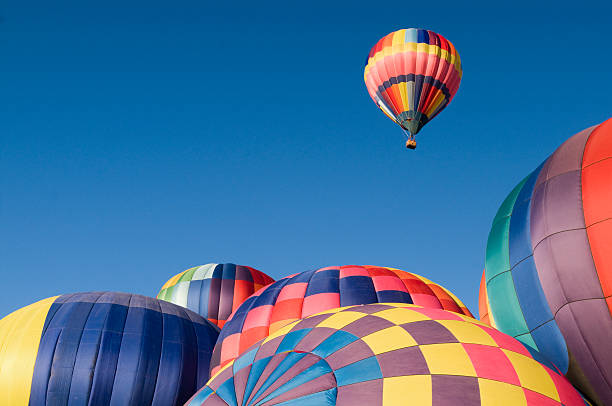 Colorful Hot Air Balloon Rising With Copy Space Hot air balloons on the ground create a colorful frame for the one that is rising above them.  A great metaphor for success or standing out from the crowd.   inflating stock pictures, royalty-free photos & images