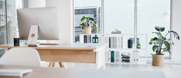 istock Empty office, interior and computer on desk in workplace, company or workspace. Room, desktop and table with corporate furniture, plants and window with modern design for business with nobody. 1573789099