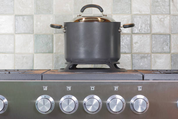 A yellow enameled cast-iron casserole steams as it cooks something on a gas stove.