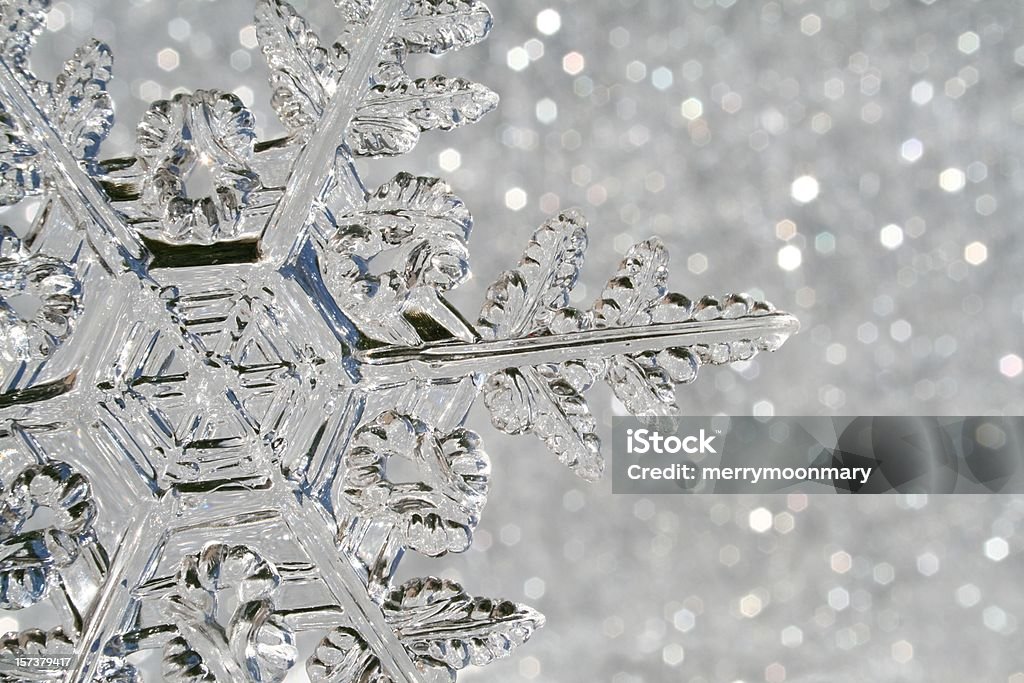 Snowflake macro A glass snowflake Christmas ornament shot in front of a sparkle background that looks like snow glittering.  Since the ornament is made from glass, it looks a little bit 'melty' with soft edges and glittery sparkle. January Stock Photo