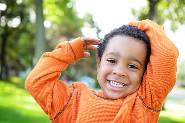 little boy con una inestimable sonrisa al aire libre - mano en el cabello fotografías e imágenes de stock