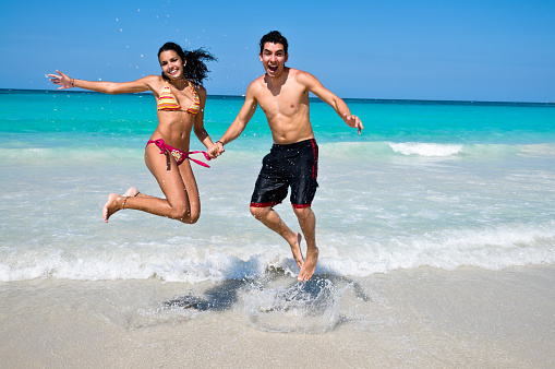 Young happy couple jumping and having fun in a Tropical white sand beach
