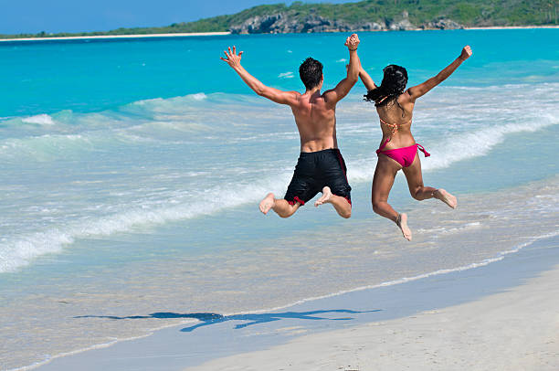 istock Young happy couple jumping holding hands in a tropical beach 157379531