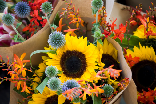 Vibrant, colorful wildflower bouquets on display in buckets at a farmer's market.