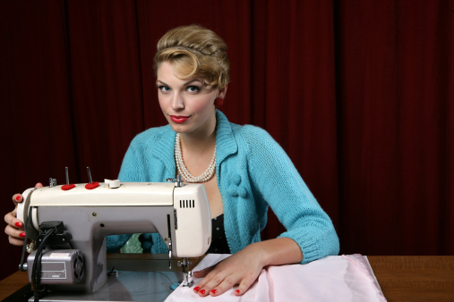 A seamstress works in a tailor's workshop using a sewing machine